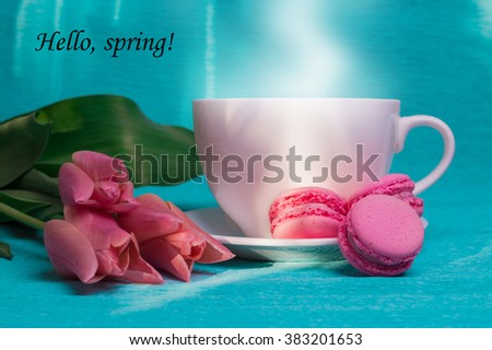 Tag hello spring with three pink tulips, a cup of coffee and three pink macaroons on blue background