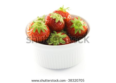 Juicy ripe red strawberries in a small round white dish on a white background