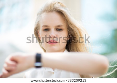 Young business woman checking the time on her watch. Royalty-Free Stock Photo #383209213