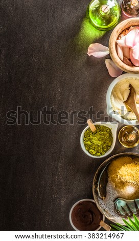 Narrow top down view of oils, salts and other body care objects in jars and cups with copy space on dark slate background