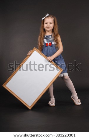 Beautiful girl holding an empty picture frame on black background