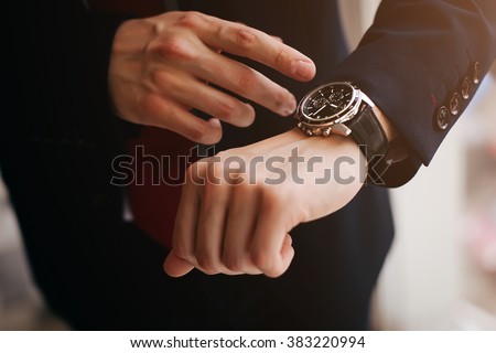 closeup designer watch on businessman hand, he looks on the time and hurrying Royalty-Free Stock Photo #383220994