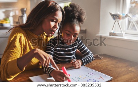 Little black girl learning to read learning the alphabet Royalty-Free Stock Photo #383235532