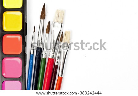 Colorful watercolor paints set with multicolored brushes isolated on white background with space for your text