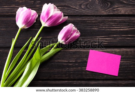 Tulips and a card on a wooden background