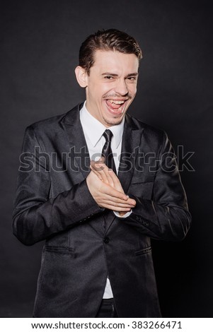 young businessman in black suit rubbing his hands together. emotions and people concept. image on a black background.