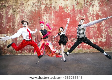 Four mimes jumping on a background of a red wall. Royalty-Free Stock Photo #383285548