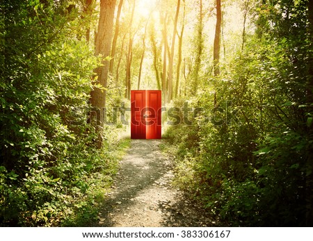 A red doorway is on a trail in the woods with trees for a concept about faith, freedom or opportunity.  Royalty-Free Stock Photo #383306167