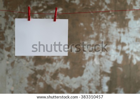 One big paper card hanging on the rope on grunge background.