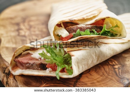 fresh homemade burritos with beef on olive cutting board shallow dof
