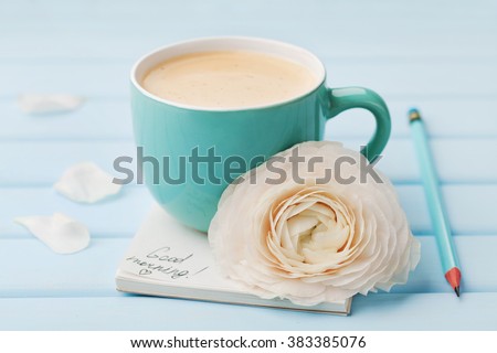 Coffee cup with spring flower and notes good morning on blue rustic background, breakfast on Mothers day or Womens day