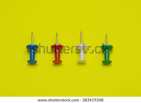 Set of push pins in different colors, isolated on yellow background.