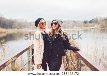 Outdoor lifestyle portrait of two best friends, smiling and having fun together, enjoy each other company posing and making selfie pictures to each other and share happiness 