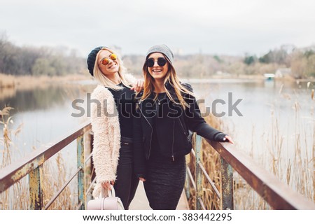 Outdoor lifestyle portrait of two best friends, smiling and having fun together, enjoy each other company posing and making selfie pictures to each other and share happiness 