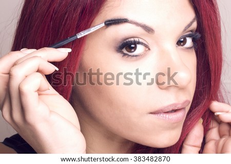 Portrait of a redhead beauty with a eyebrow brush tool tinting applicator 