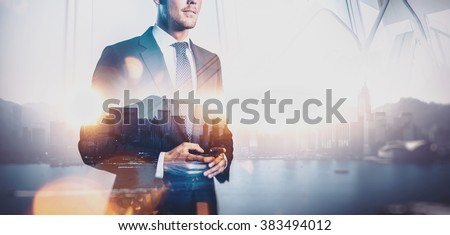 Photo of businessman holding smart phone. Double exposure photo of panoramic city view at sunrise  Royalty-Free Stock Photo #383494012