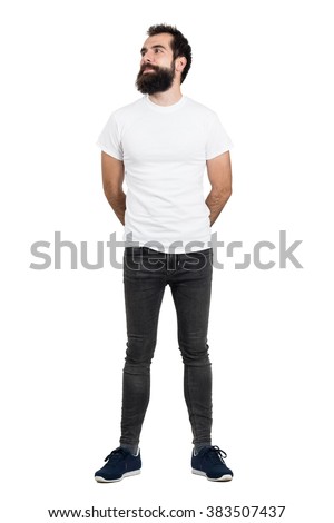 Smiling bearded man wearing white t-shirt and tight jeans looking away. Full body length portrait isolated over white studio background.  Royalty-Free Stock Photo #383507437