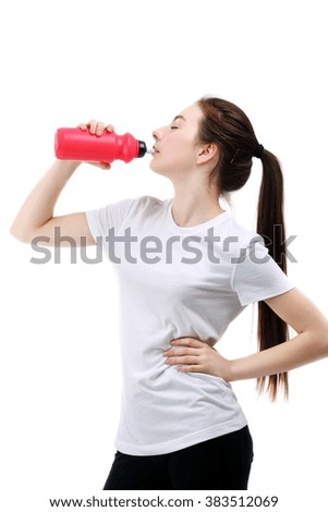 Sporty young woman drinking water on white background