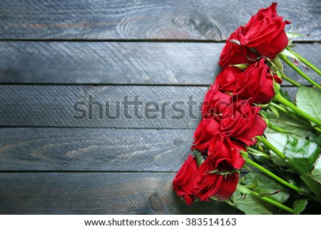 Bouquet of fresh red roses on wooden background