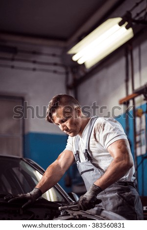 Picture of athletic man repairing car in garage