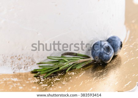 closeup decoration fresh blueberries and rosemary on cake with white cream, selective focus