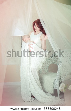 
Mom is holding the baby in the open arms on a light background