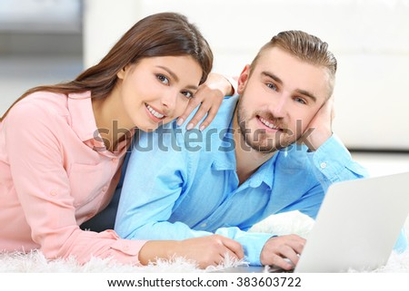Happy couple lying on the floor and working on laptop