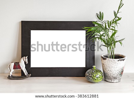 Image of a mockup scene with wooden frame, toy horse and plant pot. 