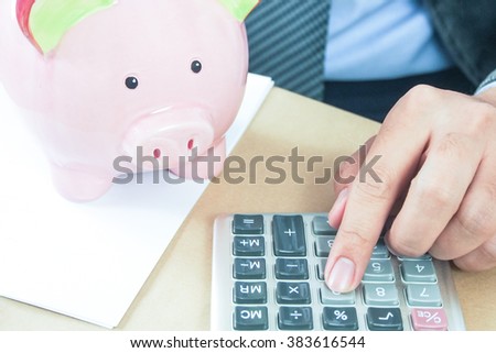business man using calculator and piggy bank on office desk