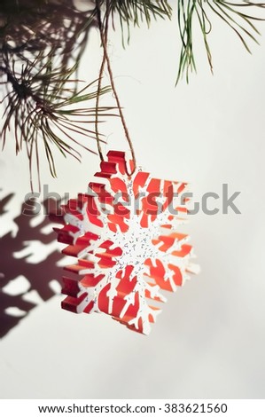 Christmas toys in the form of snowflakes hanging on a Christmas tree on a white background in daylight