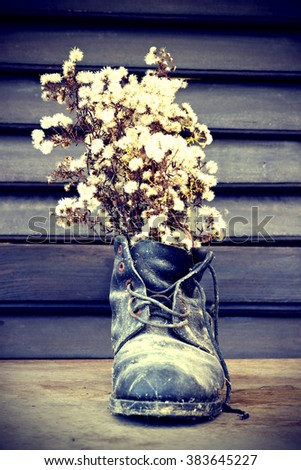 Old ruined boot is used as a vase for wild flowers - vintage stylized photo
