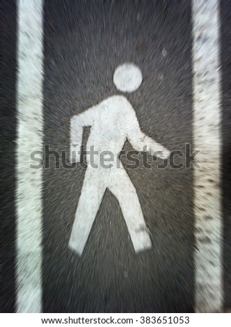 A zooming view of a walking man symbol on a tarmac road for the concept of rush hour.