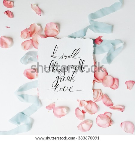 quote "Do small things with great love" written in calligraphy style on paper with pink petals and blue ribbon. Flat lay, top view