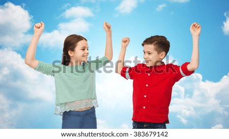 childhood, friendship, joy, gesture and people concept - happy smiling boy and girl raising fists and celebrating victory over blue sky and clouds background