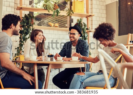 Group of friends enjoying in cafe together. Young people meeting in a cafe. Young men and women sitting at cafe table and smiling Royalty-Free Stock Photo #383681935