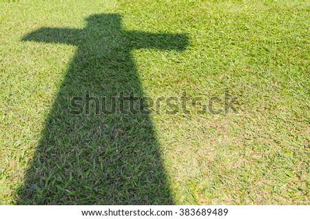 Shadow of Christian cross on green grass floor