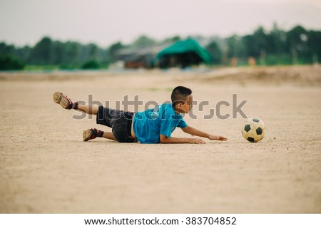 The boy is playing football as a goal keeper, he try to save the goal. A film picture filter with grain.