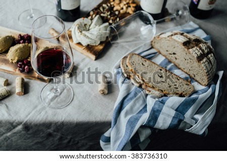 Wine appetizers: fresh bread, chicken liver pate, cheese and nuts, wine and corks on a background, on a linen tablecloth