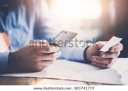 Business concept. Businessman holding hand white businesscard and making photo smartphone. New work project on the table. Horizontal mockup. Blurred effect Royalty-Free Stock Photo #383741719