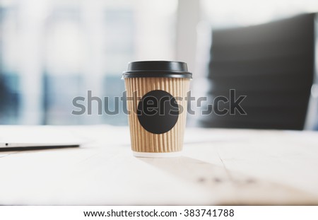 Closeup of blank craft paper coffee cup on the wood table. Space for you advertising. Horizontal mockup, blurred background