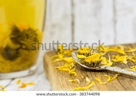 Cup of healthy marigold tea and dried marigold flowers