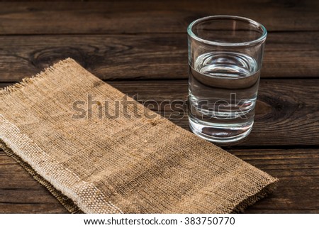 Shot of vodka with piece of cloth on an old wooden table. Close up view