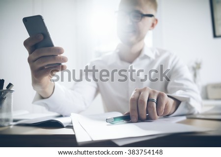 Close up of smiling businessman using modern smart phone, Young happy man working at his office and holding cellphone, manager typing text message on mobile phone