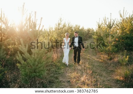 bride in a wedding dress and groom  stand in a clearing in the p