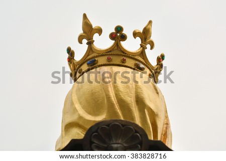 head shot of statue of king sitting in a chair wearing gold crown and yellow veil