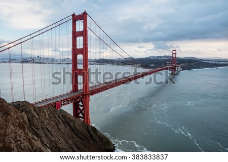 The iconic Golden Gate bridge extends across the San Francisco Bay from the Marin headlands to the beautiful city of San Francisco. The bridge is a symbol of the city and northern California. Royalty-Free Stock Photo #383833837