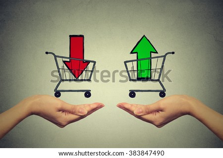 Buy or cell concept. Stock market trading. Two hands with consumer baskets with up and down arrow signs isolated on gray wall background