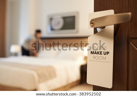 Maid cleaning the room with please make up my room sign on the door Royalty-Free Stock Photo #383952502