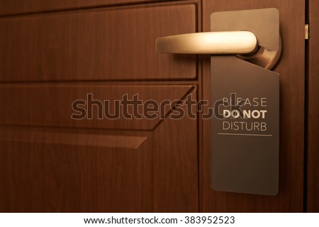 Closed door of hotel room with please do not disturb sign Royalty-Free Stock Photo #383952523
