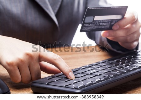 Close-up of businesswoman shopping online with credit card using mouse.